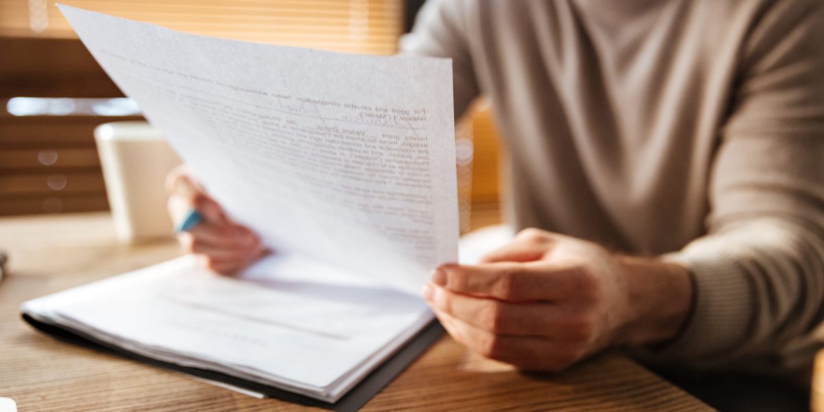 Cropped photo of attractive young man in office working with documents. Coworking.